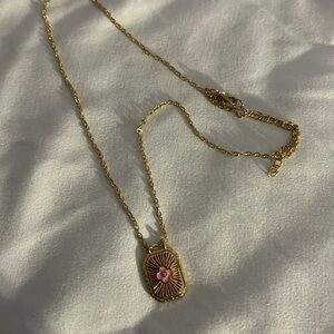 Gold chain with pendant, little pink glover in the center